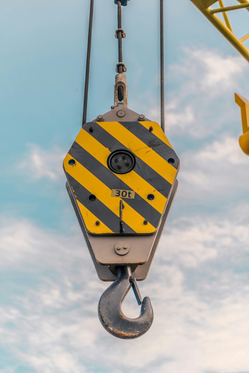 Detailed view of a heavy-duty crane hook against a clear sky in Makassar, Indonesia.